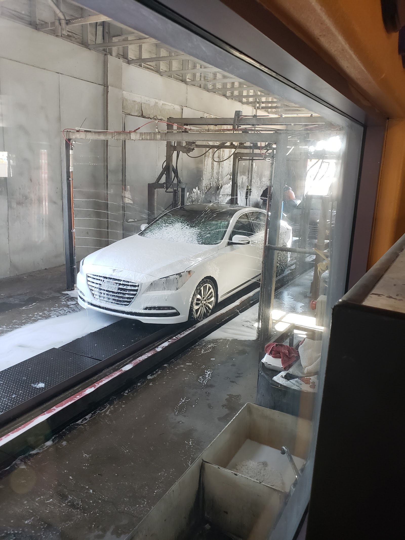 White sedan covered in foam inside the wash bay